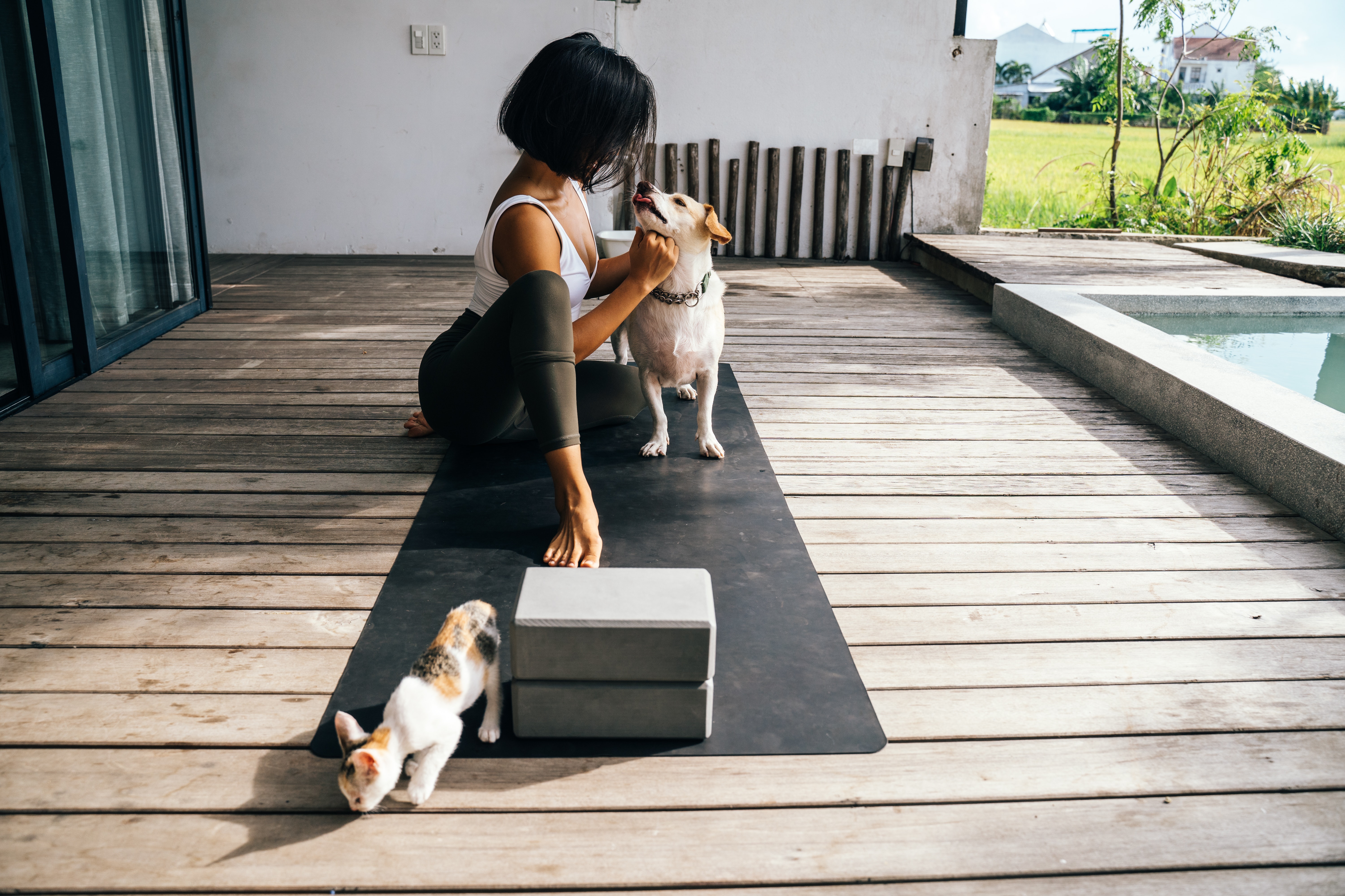 A woman on a yoga mat petting a dog